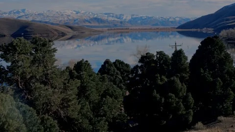 Dense green pine trees frame perfect reflection of snowy Sierra Nevada... Vidéo 328254625