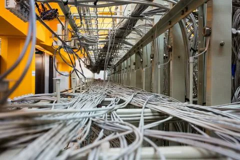 Dense grey network cables are weaving through metal cable trays in flat design Stock Photos