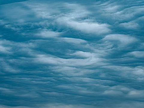 Dense, layered blue storm clouds form rippling textures across the sky. Stock Photos