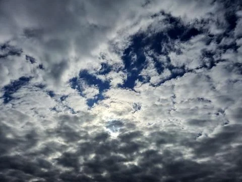 Dense layered clouds fill the sky with a bright sunlit opening in the cente.. Photos