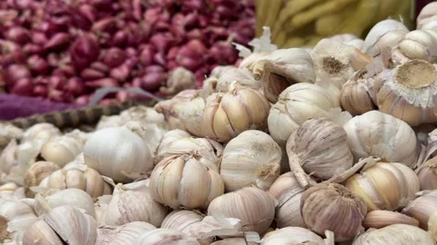 Dense layers of large garlic bulbs cover the selling surface, with stacks of red 库存影片 333358511