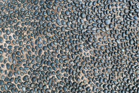 Dense pebble arrangement forming repeating textured pavement pattern Stock Photos