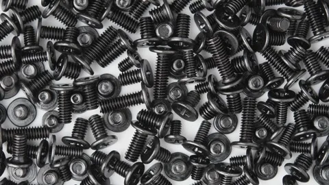 Dense pile of black computer screws rotates on white surface for hardware repair Video stock 346876326