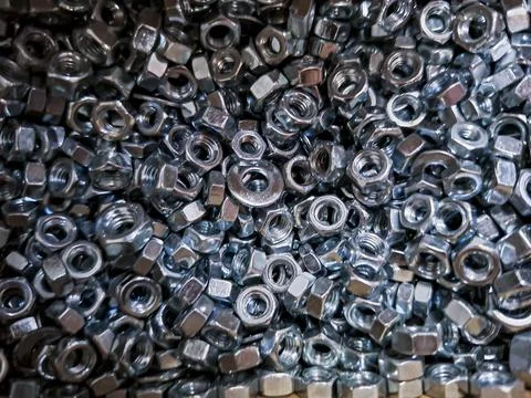 Dense pile of metal hex nuts with threads in a mechanical setting for auto .. Stock Photos