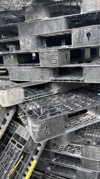 A dense pile of worn black plastic pallets with visible dirt and grime, arran Stock Photos