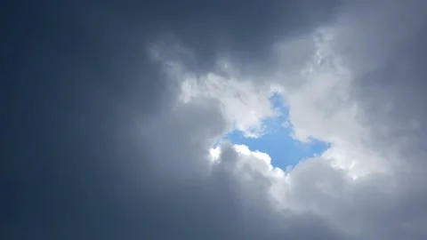 Dense rain clouds slowly closing the hole with a piece of blue sky Stock Footage 136188655