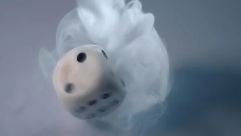 A dense stream of smoke falls on a spinning dice and spreads out to the sides Stock Footage 313182267