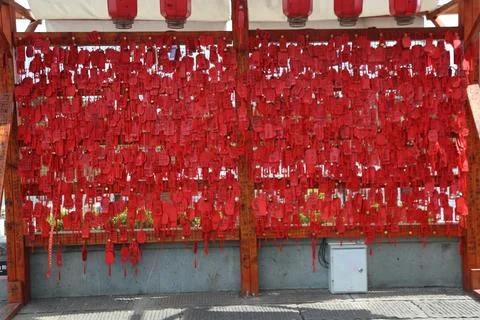 Dense wall of red hanging tags with handwritten calligraphy under a shaded .. 写真素材