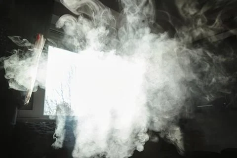 Dense white smoke clouds billowing indoors in front of a bright window back.. Stock Photos
