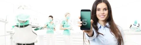 Dental care smiling woman showing smart phone on dentist clinic with dentist' Stock Photos