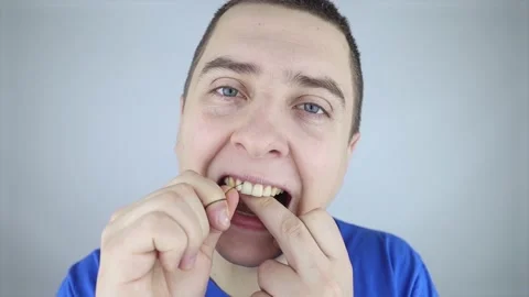 Dental floss close up. A man in front of a mirror brushes his teeth with flossin Stock Footage 168929780