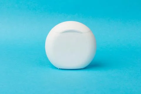 Dental floss container on blue background. Daily oral hygiene, teeth care and Stock Photos