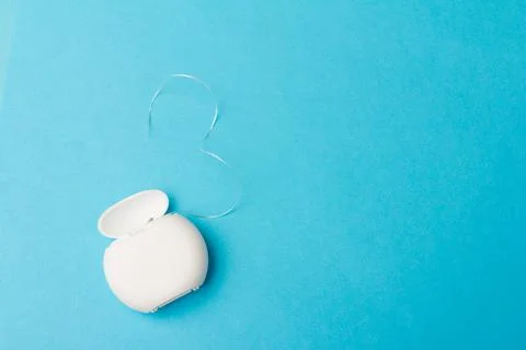 Dental floss container on blue background. Daily oral hygiene, teeth care and Stock Photos