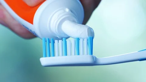 Dental Health - Squeezing white toothpaste from a tube onto a toothbrush. Video stock 114765372