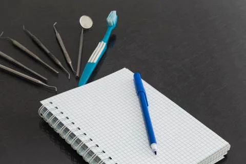 Dental instruments on gray surface with white notebook Stock Photos