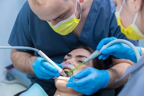 Dental Procedure Highlighting Modern Techniques: Two Dentists Perform Treatment Stock Photos