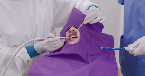 Dental procedure in progress as dentist uses curing light and suction with Stock Footage 313663071