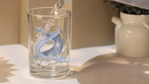 Dental retainer soaking in water with an effervescent cleaning tablet Vídeo Stock 339020797