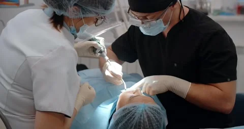 The dental surgeon does the surgery with assistant in dental clinic Stock Footage 263128264