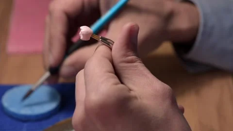 Dental technician applies ceramic material to the crown of a dental implant 動画素材 169936062