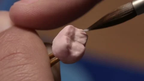 Dental technician applies ceramic material to the crown of a dental implant 動画素材 169936341