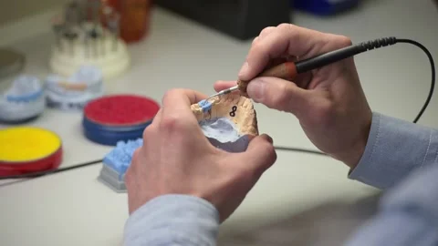 Dental technician holding a tooth model in his hands and working with wax 動画素材 169936088