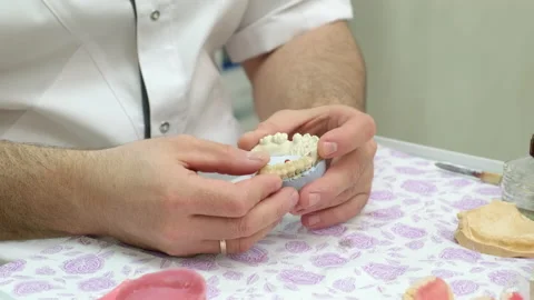 Dental technician looking at plaster cast of jaws while making denture in lab Video stock 221264507