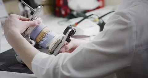 A dental technician makes a denture on a mock-up of the jaw. Stock Footage 163898309