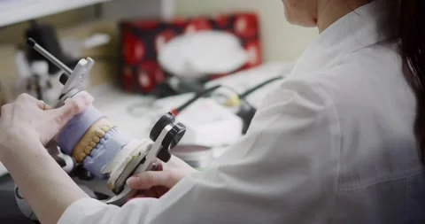 A dental technician makes a denture on a mock-up of the jaw. Stock Footage 163898666
