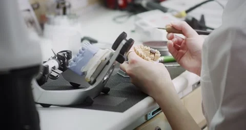 A dental technician makes a denture on a mock-up of the jaw. Stock Footage 163899393