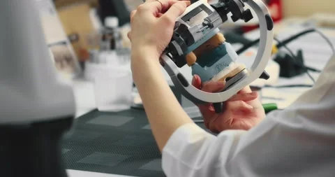 Dental technician makes a plaster cast of jaw models in an articulator. Stock Footage 199600374