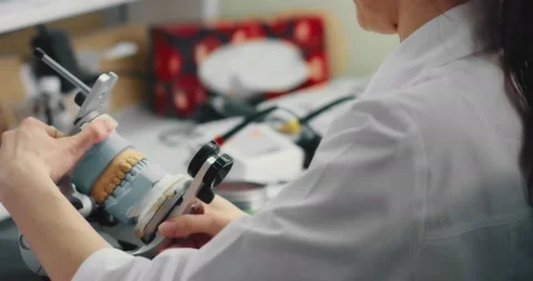 Dental technician makes a plaster cast of jaw models in an articulator. Stock Footage 199600631