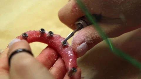 A dental technician processes a removable denture on a micro motor Stock Footage 212142773