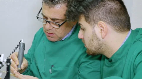 Dental technician - prosthodontics teaches how to use a drill to an apprentice Stock Footage 59936331