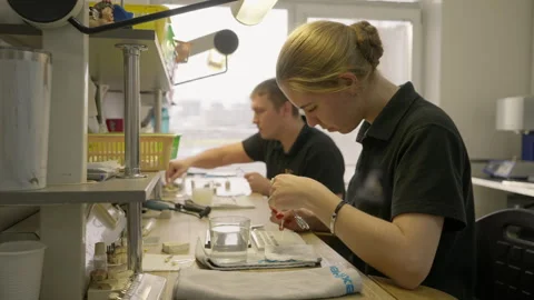 Dental technician specialist using small tools for fake teeth production Stock Footage 248557617