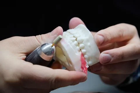 Dental technician using a drill to adjust and polish a large jaw model. Stock Photos