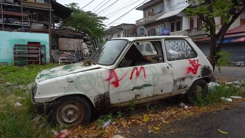 Dented Car Wreck With Smashed Windows and Graffiti in Bad Neighborhood Stock Footage 128664773