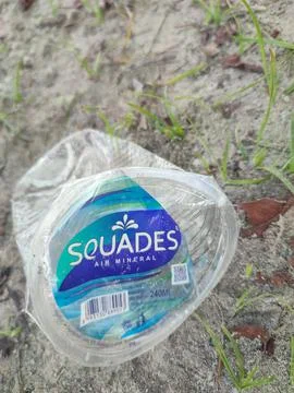 Dented plastic cup on a sandy field. Stock Photos