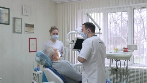 Dentist and assistant are talking to elderly patient before examination in 库存影片 170807777
