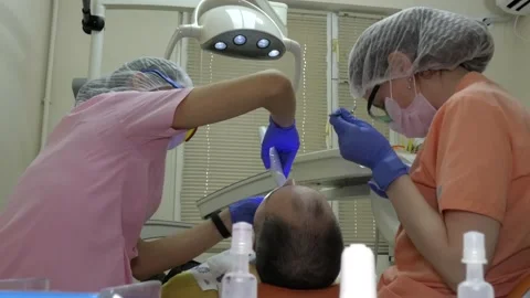 A dentist and an assistant are treating a man's teeth. Stock Footage 147728464
