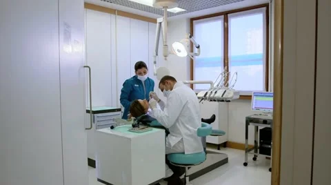 Dentist and assistant checking dental hygiene of female client Stock Footage