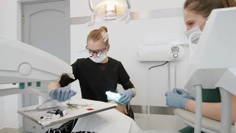 Dentist and assistant remove blue rubber dam from patient mouth after work 库存影片 330179204