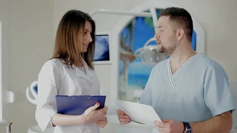 Dentist and assistant talking about further treatment the patient's teeth Stock Footage 104353386