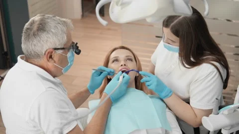 The dentist and assistant work carefully on the treatment of the tooth, ensuring Stock Footage 252130951