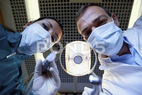 Dentist and assistant working and filling tooth to sick patient Stock Photos