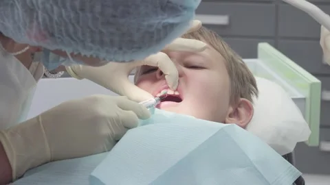 Dentist applies plaque disclosing solution on boy's chipped tooth Stock Footage 330482788