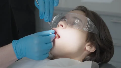 Dentist applying topical anesthesia to child gum using cotton applicator Stock Footage 330294973