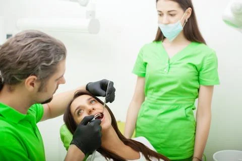 Dentist are treating teeth to client in dental office Stock Photos