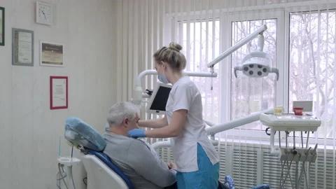 Dentist assistant in protective mask preparing elderly patient to examination in Stock-Footage 170807718