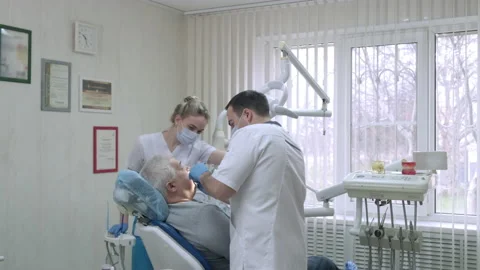 Dentist with assistant in protective masks working with patient in dental clinic Video stock 171168733
